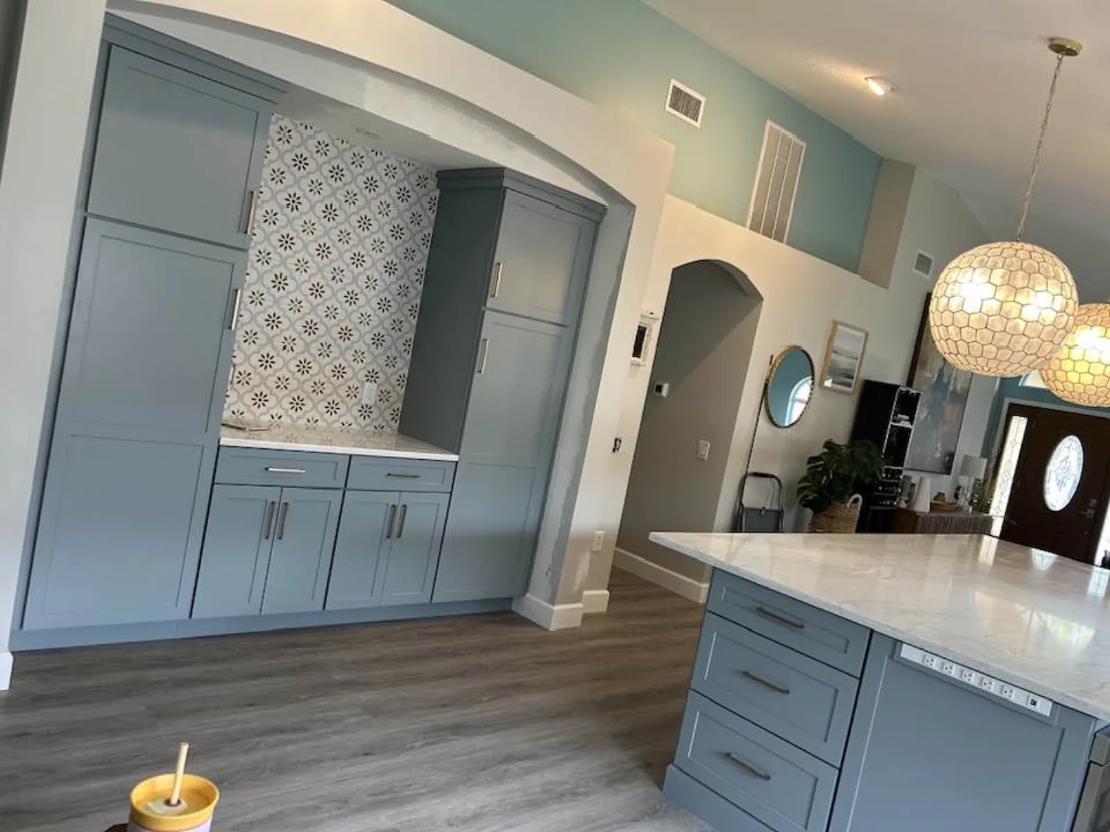Blue built-in arched cabinetry with patterned tile backsplash and pendant lighting