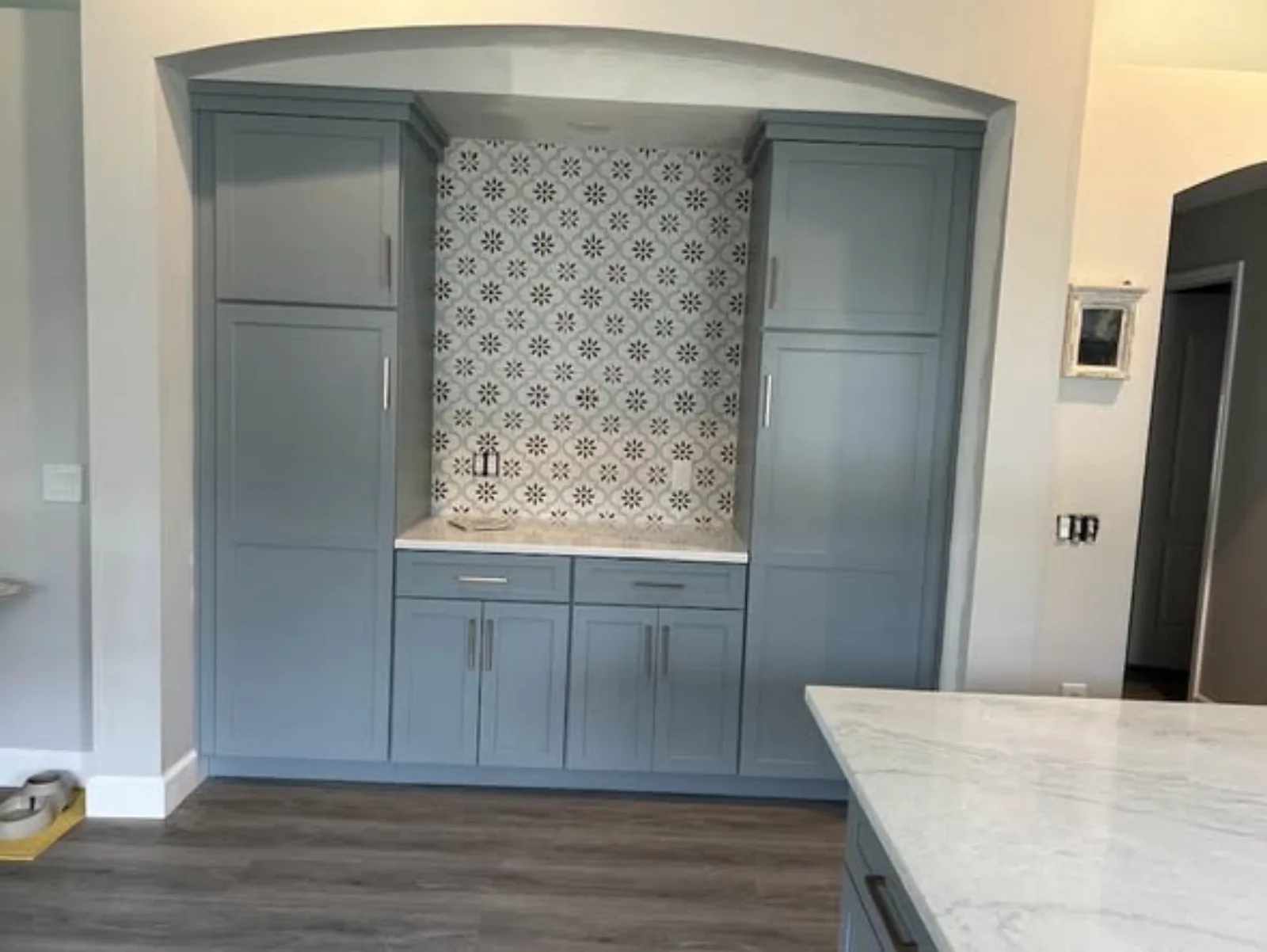Detail of blue built-in cabinetry framing a decorative tile feature wall
